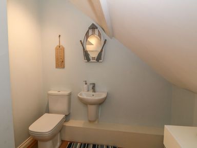 A small bathroom with a toilet sink mirror and wall decoration at Fishermans Cottage in Malltraeth