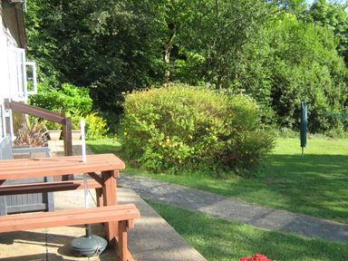 An outdoor garden area with a wooden picnic table pathway and bushes at 8 The Park in Kilkhampton