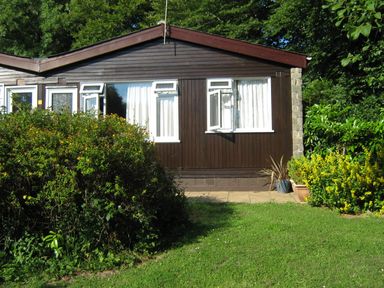 A bungalow with open windows surrounded by greenery and plants at 8 The Park in Kilkhampton