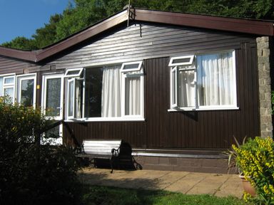 Exterior view of a single-story building with white framed windows and a bench in front at 8 The Park in Kilkhampton