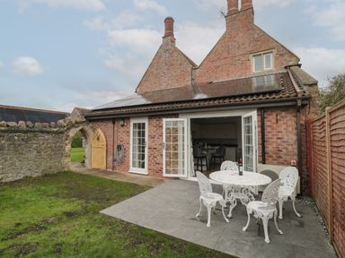 A patio with white metal table and chairs outside a brick house with solar panels at The Hideaway in Lympsham near Brean