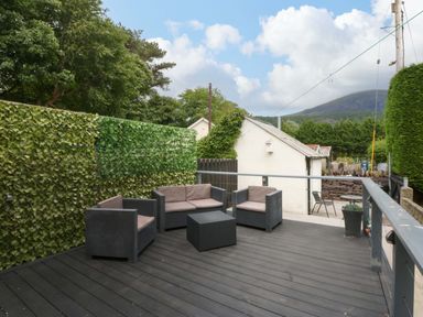 A seating area with chairs and a table surrounded by plants at Y Berth in Caernarfon