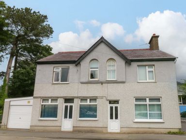 A house with a garage and trees in front at Y Berth in Llanberis