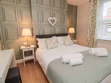 A bedroom with a double bed two bedside tables with lamps and rolled towels at Redshank in Amble