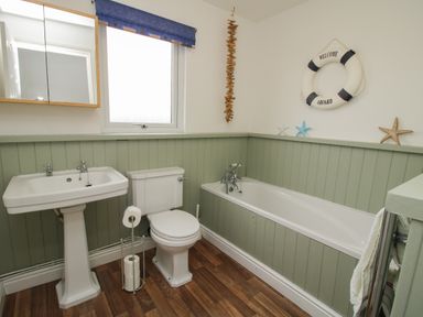 A bathroom with a pedestal sink toilet and bathtub with green paneling and nautical decor at Dragonfly Lodge Worthen near Minsterley