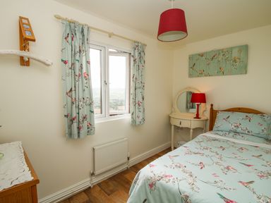 A bedroom with a single bed a window with curtains a dressing table and a dresser at Dragonfly Lodge in Worthen near Minsterley