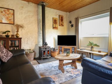 A living room with a wood stove television and wooden furniture at Tyn Y Cefn Near Blaenau Ffestiniog