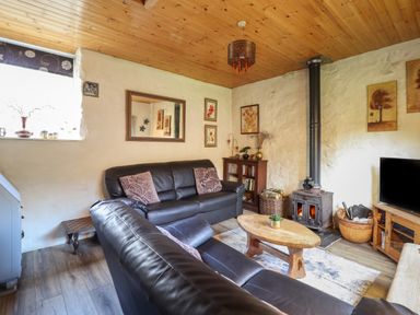 A living room with leather sofas wood stove coffee table and television at Tyn Y Cefn Near Blaenau Ffestiniog