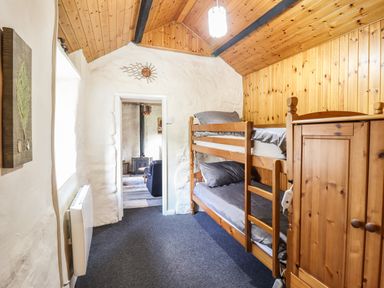 A bedroom with bunk beds and a wooden wardrobe at Tyn Y Cefn Near Blaenau Ffestiniog