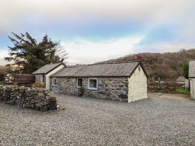 A stone cottage with a gravel yard and stone wall at Tyn Y Cefn Near Blaenau Ffestiniog