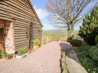 An outdoor area with a gravel path wooden fencing trees and plants at The Retreat in Pedairffordd near Llanrhaeadr-Ym-Mochnant