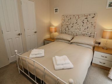 A bedroom with a double bed two bedside tables with lamps and folded towels on the bed at Number 15 in Carnforth