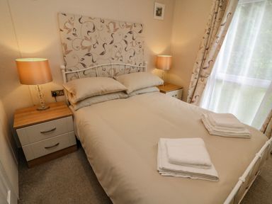 A bedroom with a double bed bedside tables with lamps and folded towels on the bed at Number 15 in Carnforth