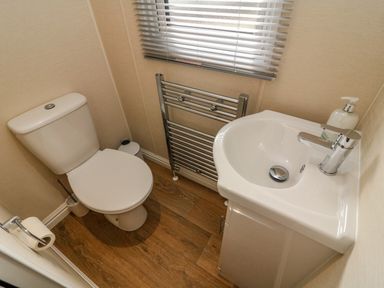 A small bathroom with a toilet sink towel radiator and window blinds at Number 15 in Carnforth