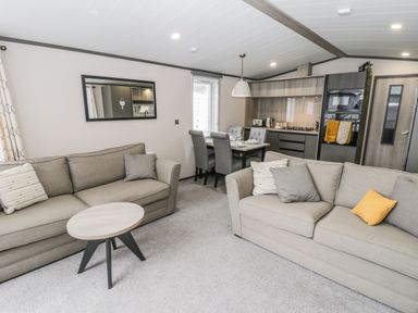 A living room with two sofas a small round table and a dining table with chairs in a kitchen area at Finch 59 in Cayton