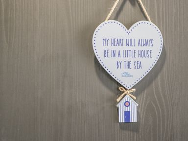 A heart shaped sign hanging on a wall with a small striped house attached at Finch 59 in Cayton