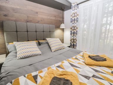A bedroom with a grey padded headboard patterned pillows and matching curtains at Finch 59 in Cayton