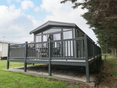 A modern static caravan with a raised deck and outdoor furniture at Finch 59 in Cayton