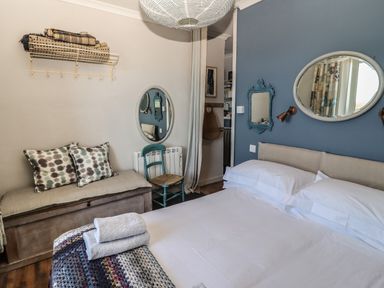 A bedroom with a bed towels on a blanket a bench with cushions and a chair at Starfish in Sennen Cove