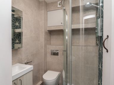 A small bathroom with a toilet sink cabinet and a glass enclosed shower at Starfish in Sennen Cove