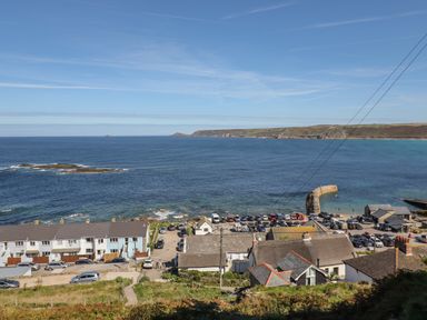 A coastal village with houses cars and a stone pier by the sea at Starfish in Sennen Cove