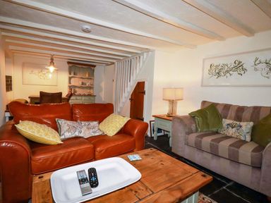 A living room with a brown sofa, coffee table, and lamp at Woodview in Looe