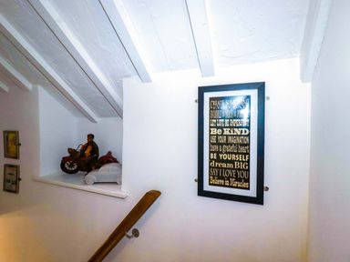 A staircase with figurines and a framed poster at Woodview in Looe