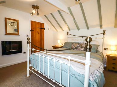 A bedroom with a bed and a fireplace at Woodview in Looe