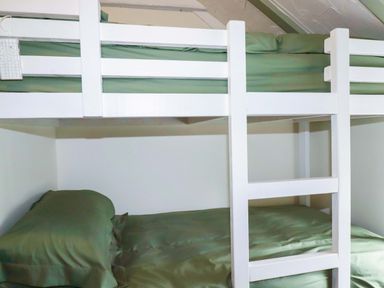 A bunk bed with green bedding at Woodview in Looe