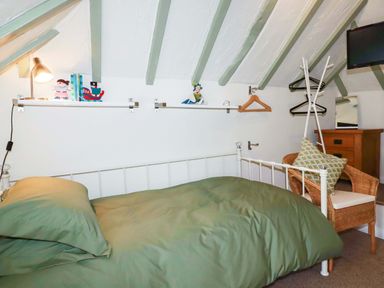 A bedroom with a bed and decorative items on shelves at Woodview in Looe