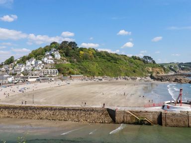 A beach scene with people and a pier at Woodview in Looe