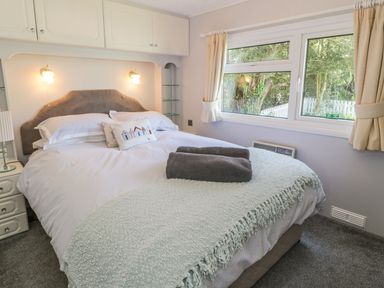 A bedroom with a double bed bedside tables lamps and a window with curtains at Orchard Lodge Llanengan near Abersoch