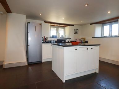 A kitchen with a refrigerator an island with cabinets and a countertop at Penpethy Farm in Tintagel