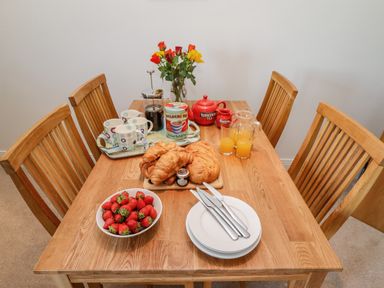 A wooden dining table with croissants strawberries orange juice tea set cups and knives at Above & Beyond Whitby