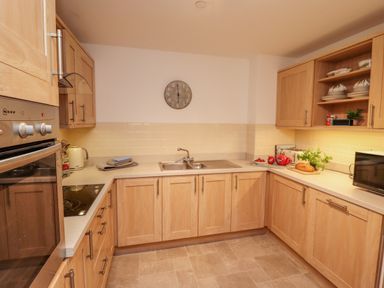 A kitchen with wooden cabinets a wall clock and a sink at Above & Beyond in Whitby