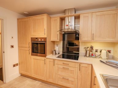A kitchen with wooden cabinets an oven a stovetop and kitchen utensils at Above & Beyond in Whitby
