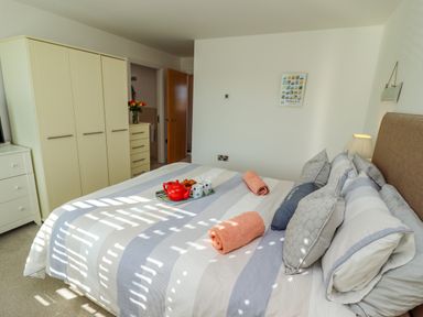 A bedroom with a bed with pillows and towels a wardrobe and a chest of drawers at Above & Beyond in Whitby