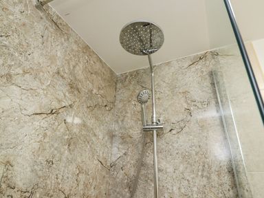 A shower area with a dual showerhead and marble walls at Above & Beyond in Whitby