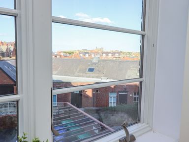 A view of rooftops and buildings through a window with white frames at Above & Beyond in Whitby