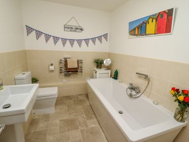 A bathroom with a bathtub sink toilet flowers and wall decorations at Above & Beyond in Whitby