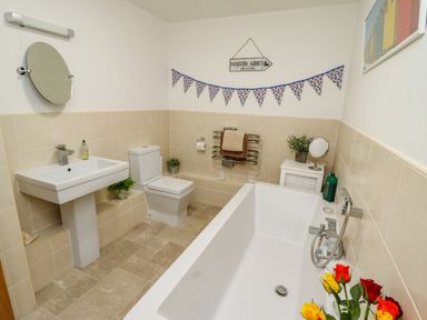 A bathroom with a bathtub flowers a toilet a sink and wall decorations at Above & Beyond in Whitby