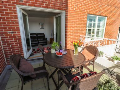An outdoor patio with a round table and four chairs with cushions and a vase of flowers on the table at Above & Beyond in Whitby