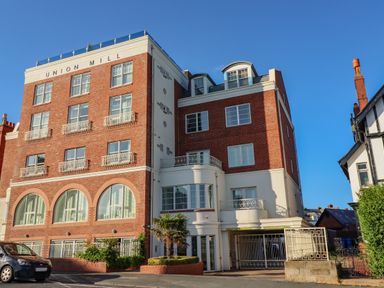 A brick apartment building named Union Mill with windows and balconies and a car parked outside at Above & Beyond in Whitby