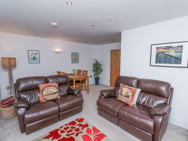A living room with two brown leather sofas and a dining table at Above & Beyond in Whitby