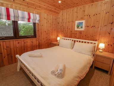 A bedroom with a white bed and rolled towels on it in Lodge 16 in Lanteglos near Camelford