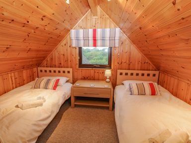 A bedroom with two single beds a bedside table and a window at Lodge 16 in Lanteglos near Camelford