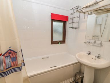 A bathroom with a bathtub sink mirror window and shower curtain at Lodge 16 in Lanteglos near Camelford