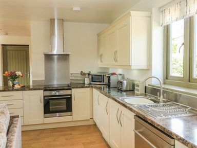A kitchen with a stove oven microwave toaster and sink with window at The Mews in Bovey Tracey near Chudleigh Knighton