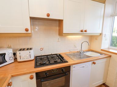 A kitchen with a stove toaster microwave sink dishwasher and cabinets at Maypole Cottage in Fylingthorpe