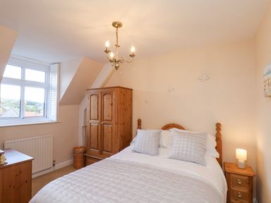 A bedroom with a double bed pillows bedside table wardrobe and window at Maypole Cottage in Fylingthorpe